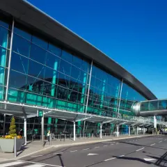 Nowoczesny terminal lotniska w Irlandii, z przeszkloną fasadą i mostem łączącym budynki.
