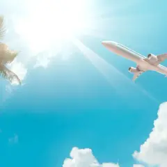 Samolot leci na tle błękitnego nieba z palmami, jakby to był bilet lotniczy na wakacje.