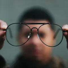 Osoba trzyma okulary, które mogą pomóc w przypadku niedowidzenia na jedno oko, co może być podstawą do ubiegania się o rentę.
