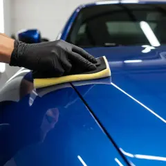 Nakładanie ceramiki na auto to inwestycja w jego wygląd i ochronę. Rękawiczka z gąbką rozprowadza produkt po lśniącym lakierze.