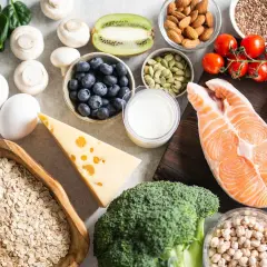 Vielfältige Lebensmittel für Muskelaufbau: Lachs, Hähnchen, Eier, Haferflocken, Beeren, Nüsse, Brokkoli, Käse und mehr.