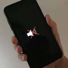 Dłoń trzyma czarny telefon z wyciszonym głośnikiem. Zastanawiasz się, dlaczego głośnik w telefonie trzeszczy?