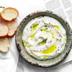 Labneh co to? Kremowy, gęsty serek z jogurtu, skropiony oliwą i ziołami, podany z chrupiącym pieczywem.