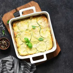 Sformato dorato con zucchine e patate, guarnito con basilico fresco. Un'idea gustosa per le tue ricette con zucchine e patate.