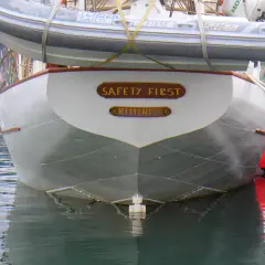 La poppa di una barca con la scritta "SAFETY FIRST RIMINI". Il suo mascone, simbolo di sicurezza, è ben visibile.
