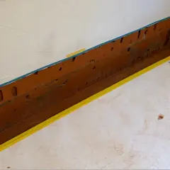 Vorbereitung für die Kellerabdichtung: weiße Folie schützt Wand, gelbes Band markiert den Bereich.