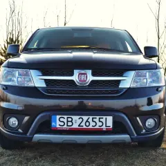Czarny Fiat Freemont na tle drzew. Zastanawiasz się nad jego spalaniem? Ten SUV oferuje przestronne wnętrze i komfort podróżowania.