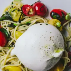 Une belle recette burrata avec des pâtes, des tomates cerises rouges et jaunes, et des herbes fraîches.