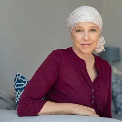 Uśmiechnięta kobieta w chuście na głowie, symbol nadziei i siły. Jej samopoczucie po chemioterapii jest widoczne w oczach.