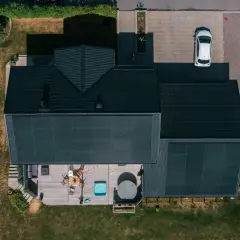 Tak med solceller fångar solens energi. Ett modernt hus med altan, bubbelpool och en vit bil på uppfarten.