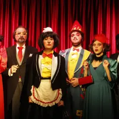 Sei personaggi in costume, forse per la cantatrice calva trama, posano davanti a una tenda rossa.