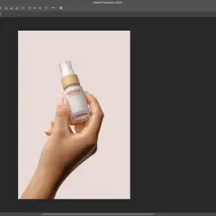 Dłoń trzymająca buteleczkę kosmetyku na jasnym tle. Program Photoshop pokazuje narzędzia, jak usunąć tło ze zdjęcia, aby wyizolować produkt.