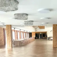 Elegancka sala weselna z kryształowymi żyrandolami i długim stołem. Zastanawiasz się, ile pieniędzy na ślub?