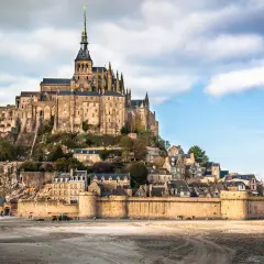 Mont-Saint-Michel, średniowieczny zamek na wyspie we Francji, z widokiem na piaszczyste wybrzeże.