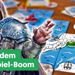 Ein Ritter mit Kapuze und Rüstung blickt auf bunte Karten mit Schiffen und Leuchttürmen. Ein Bericht über den Kickstarter-Brettspiele-Boom.