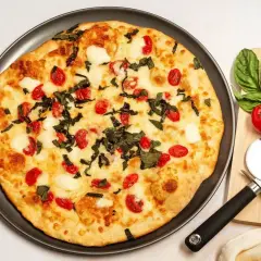 Pyszna pizza z serka wiejskiego, pomidorkami koktajlowymi i bazylią. Idealna na szybki obiad.