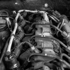 Silnik samochodowy, widok z góry. Widać przewody, wtryskiwacze i korek wlewu oleju z napisem "To avoid damage to engine oil must not exceed max". Może to oznaczać, że jest za dużo oleju w aucie.