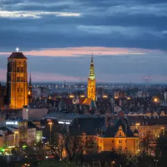 Wieczorny widok na zabytkowe centrum Gdańska, część m trójmiasto. Dominują iluminowane wieże Bazyliki Mariackiej i Ratusza Głównego Miasta.