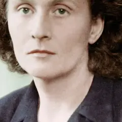 Portret Catherine Dior z zielonymi oczami i kręconymi włosami, w ciemnej marynarce.