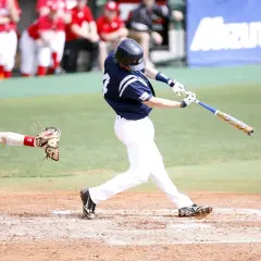 Pałkarz uderza piłkę, łapiąc ją w locie. To kluczowy moment w grze, gdzie zasady baseballu decydują o wyniku.