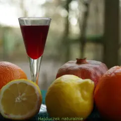 Szklanka z czerwonym płynem, obok pomarańcze, cytryna i granat. Czy to grenadyna? Hajduczek naturalnie.