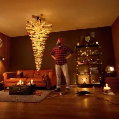 Mann steht vor umgedrehtem Holz-Weihnachtsbaum mit Lichtern. Tolle alternativen zum Weihnachtsbaum für ein modernes Zuhause.