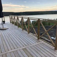 Nybyggd altan med räcke av skarva reglar. Vacker utsikt över sjö och skog.
