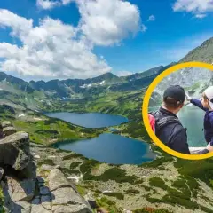 Ojciec i dziecko na szlaku w Dolinie 5 Stawów. Chłopiec wskazuje na jezioro, podziwiając górski krajobraz.