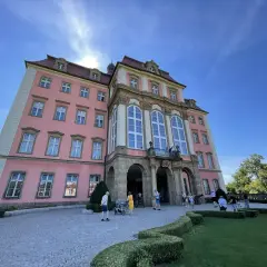 Zamek Książ, malowniczo położony, łatwy dojazd PKP. Turyści zwiedzają barokową budowlę w słoneczny dzień.