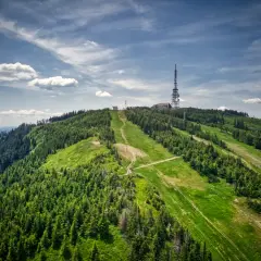 Widok na zielone **beskidzkie szczyty** z wieżą telekomunikacyjną na szczycie.