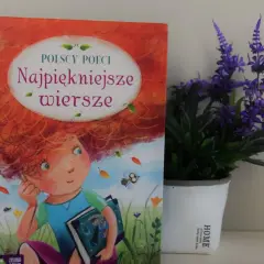 Książka "Najpiękniejsze wiersze polskich poetów" z ilustracją dziewczynki z rudymi włosami, obok doniczki z fioletowymi kwiatami.