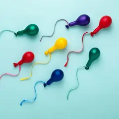 Kolorowe balony w kształcie plemników, symbolizujące kobiecy wytrysk, unoszą się na błękitnym tle.