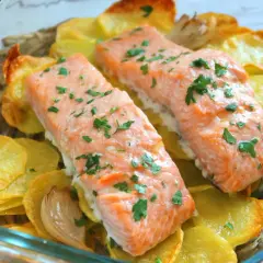 Dos filetes de salmón al horno con patatas doradas y perejil picado, listos para servir.