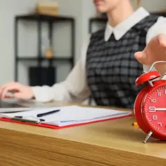 Kobieta wyłącza budzik, zastanawiając się, czy można pracować 13 godzin dziennie.