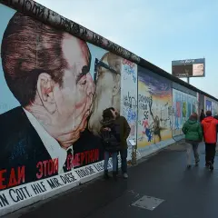 East Side Gallery Berlin: para zakochanych całuje się na tle słynnego malowidła "Braterki" Breżniewa i Honeckera.