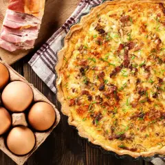 Comment faire une quiche : ingrédients pour une quiche savoureuse : œufs, lardons, et une belle quiche dorée prête à être dégustée.