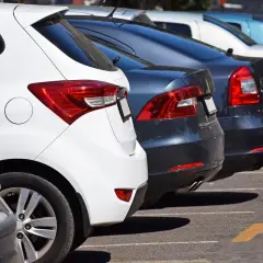 Rzędy samochodów na parkingu, w tym biały i ciemny, mogą być pomocne, gdy zastanawiasz się, jak sprawdzić auto ze Szwecji.