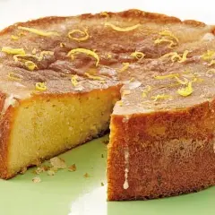 Szybkie ciasto bezglutenowe, lekko zarumienione, z cytrynową skórką na wierzchu, prezentuje się apetycznie.