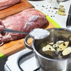 Przygotowanie solanki do schabu do wędzenia. Sól z łyżki trafia do garnka z wodą, liśćmi laurowymi i pieprzem.