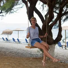 Kobieta na huśtawce na plaży w Grecji. Październikowa pogoda sprzyja relaksowi nad morzem, mimo że słońce nie jest już tak gorące.