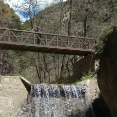 Puente metálico sobre cascada en la fabriquilla laujar. Una persona observa el agua.