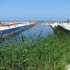 Słoneczny dzień nad kanałem w Karwi. Ludzie odpoczywają na plaży, a woda przyciąga do kąpieli. To jedna z wielu atrakcji w okolicy.