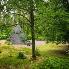 En grå pyramid reser sig ur en lummig skog. En perfekt plats för udda utflykter i Småland, med bänkar för vila.