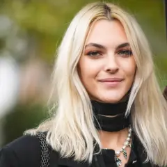 Mujer joven con pelo rubio platino, ¿qué color de pelo me favorece? Suave sonrisa, collar de perlas y pañuelo negro.