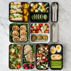 A colorful bento box diet spread with sandwiches, fruit salad, chicken, pasta, and snacks, perfect for a healthy lunch.