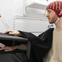 Joel Svenningsson med EEG-hjälm och en robotarm som interagerar med hans hand.