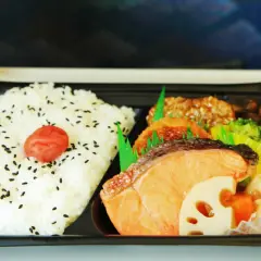 A delicious eki bento with rice, salmon, fried items, broccoli, and sausage, ready for a journey.