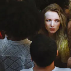 Eine Frau mit blauen Augen blickt ängstlich in eine Menge, die wie ein Albtraum Bedeutung hat.