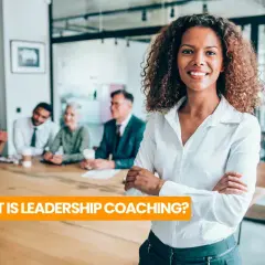 A confident woman leads a team meeting, embodying the essence of leadership coaching definition.