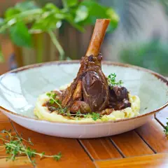 Une souris d'agneau braisée, servie sur une purée onctueuse et garnie de thym frais. Un plat savoureux et réconfortant.